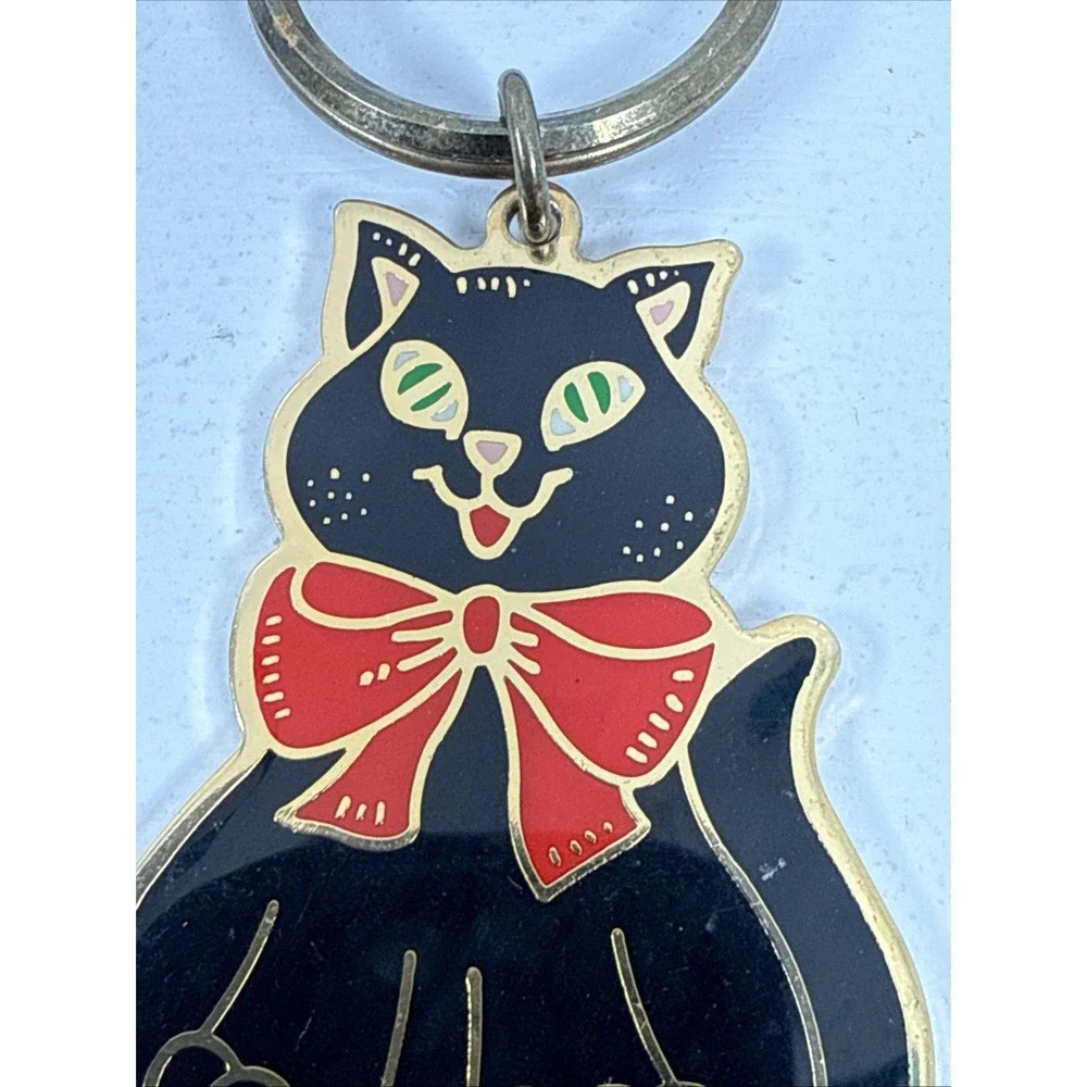 Black cat enamel keychain with gold-toned metal accents and‎ a red bow